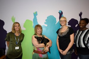 Left to right: San Diego Youth Services Storefront Shelter staff Sarah Merrill, Jan Stankus, Carly Graber, and Nytasha Thomas, with silhouettes of the youth they work with, and on-site therapy dog, Sunshine. 